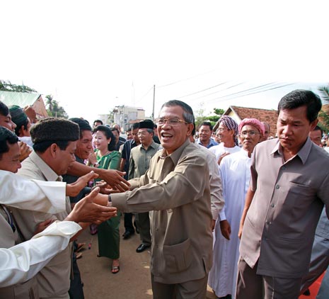 Prime Minister Hun Sen and his wife Bun Rany are greeted during a visit to a province