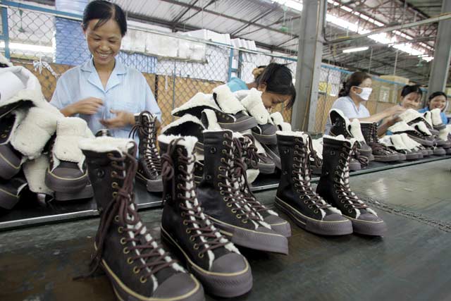 Photo: Hoang Dinh Nam/AFP.  Sole mate: workers sew shoes inside a factory in Hanoi.