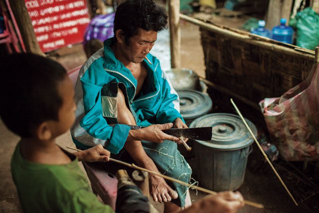 A father and son whittle sticks near the Don Sahong dam site