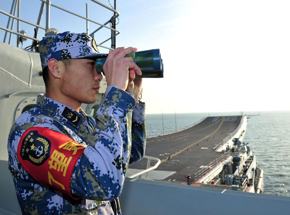 Decked out: Chinese Marines stand guard on China’s first aircraft carrier Liaoning, as it travels towards a military base in Hainan province