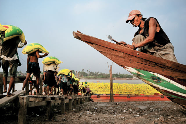 A heavy load: Workers carry sacks of rice to a barge on the Yangon River. Work on the docks pays roughly $3 per day.  Chang Chien-Chi (USA)