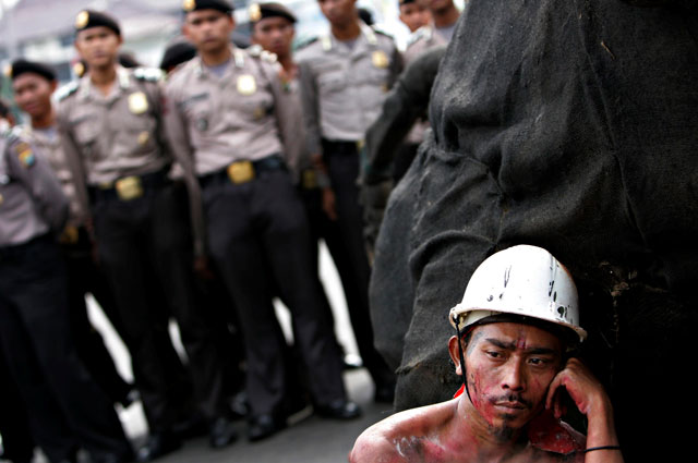 Stop. Listen. Collaborate: a weary-looking Indonesian carpenter listens to speeches at a rally to commemorate International Labour Day. Ed Wray/AP 