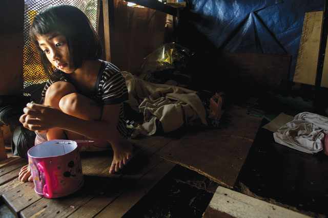 Play time: Leo Castellero’s daughter Angelica, age 5, plays with some discarded toys in their shack above the train tracks. Photo: Luc Forsyth