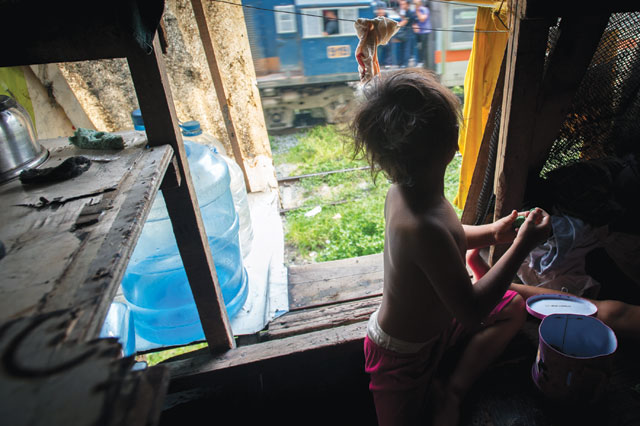 Life on the edge: Leo’s youngest son, age 3, watches as a commuter train speeds past. Photo: Luc Forsyth