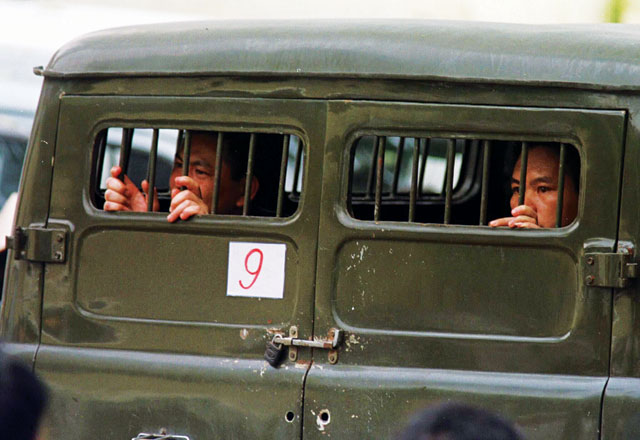 Banged up: defendants peer out from behind the bars of a police car as they arrive at the Hanoi People’s Court. Photo: Reuters