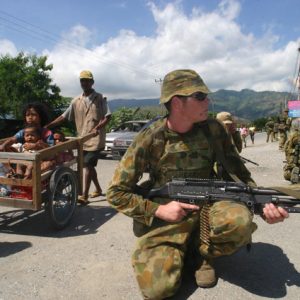 Show of strength: an Australian soldier secures an area while residents flee their homes in Dili in May 2006. Photo: Reuters