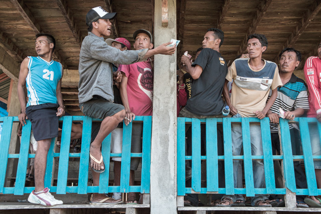 Adult men place bets during a race. Photo by Putu Sayoga