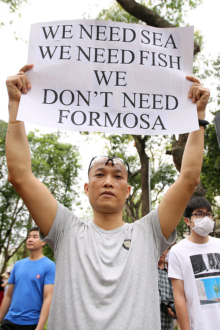 A protester holds a banner during a rally denouncing the Vietnam waste spill