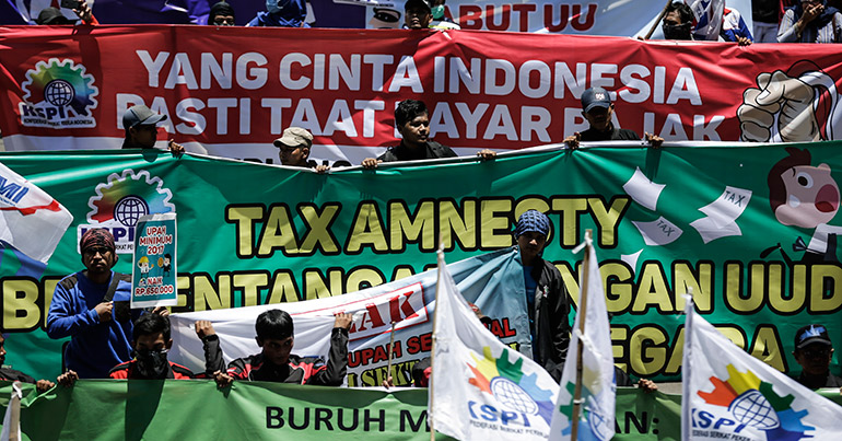 Indonesian labourers hold banners as they march toward the presidential palace during a rally in Jakarta, Indonesia