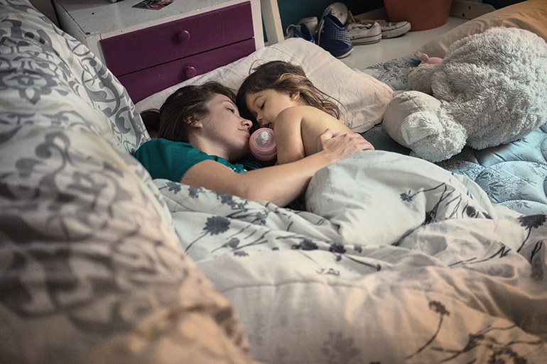 Elizabeth Beach and her daughter Kathleen lie in bed together in St.Augustine, Florida, where they are visiting Ly Hov’s uncle who he fled Cambodia with as a young child