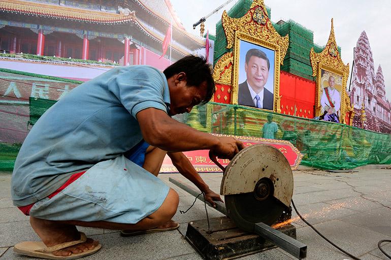 A Cambodian worker prepares portraits of Chinese President Xi Jinping and Cambodian King Norodom Sihamoni in Phnom Penh, Cambodia, 11 October 2016