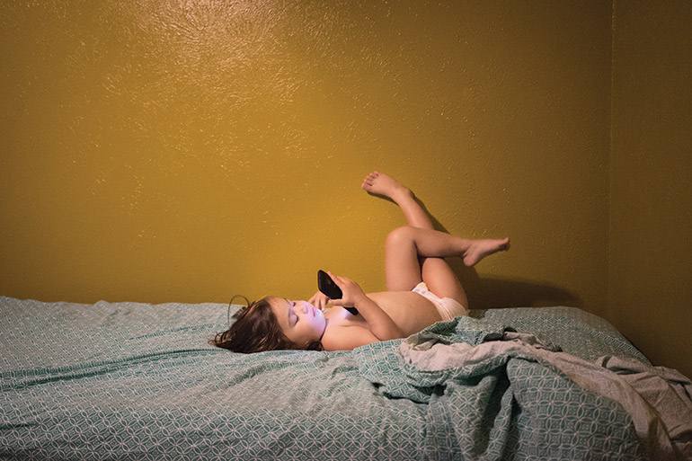 Kathleen plays with her mother’s phone in her bed in Dallas, Texas. At three years of age, Kathleen has already lived in three different countries: the US, Cambodia and South Korea