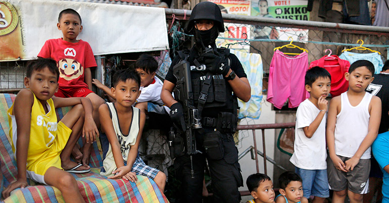 an armed Filipino member of the Special Weapons and Tactics (SWAT) team (C) standing guard as children look on during an anti-drug operation at an informal settlers community in Pasig city, east of Manila, Philippines, 09 November 2016