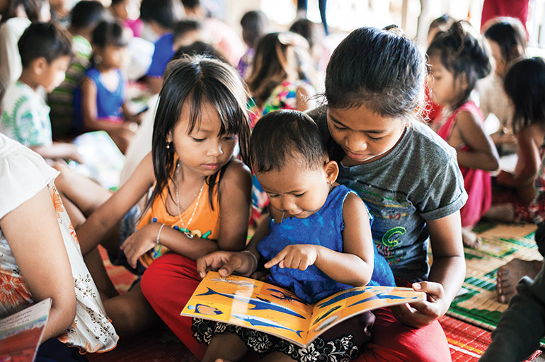 Young children read a picture book during a mobile library session put on by Sipar.