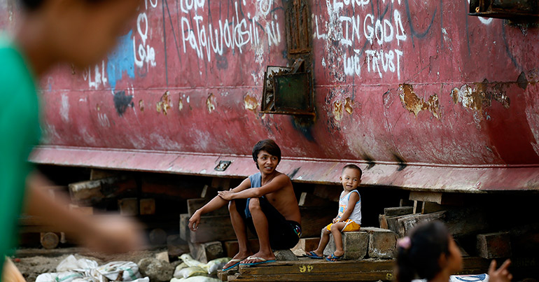 Children play in front of a ship washed ashore by the 2013 Typhoon Haiyan in Anibong village, Tacloban City, Philippines