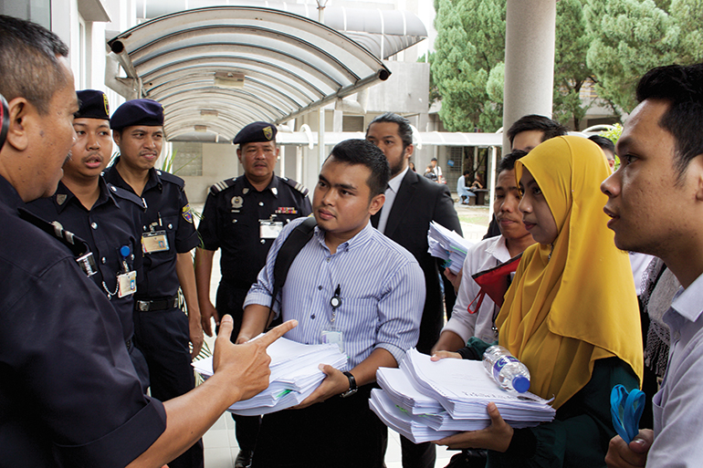 four students found guilty of participating in the Tangkap MO1 rally walk into a hearing