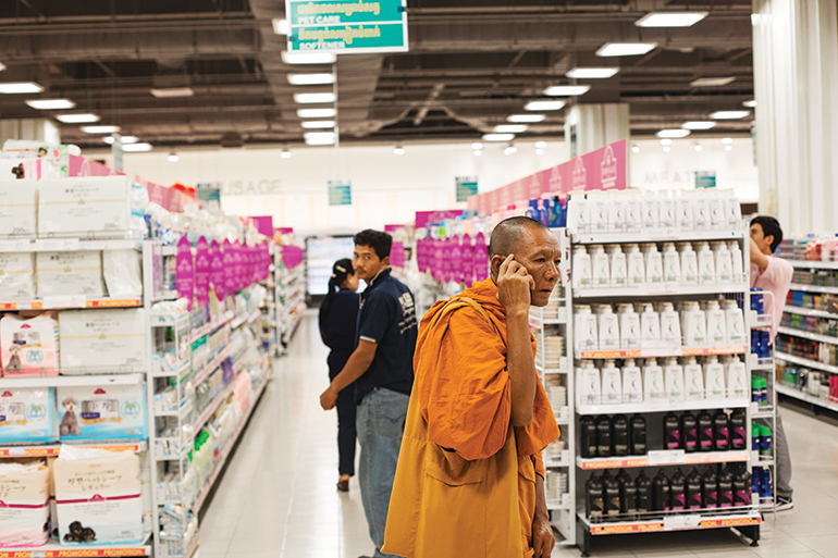 An older monk speaks on his mobile phone while walking through the shopping aisles in Phnom Penh’s Aeon Mall