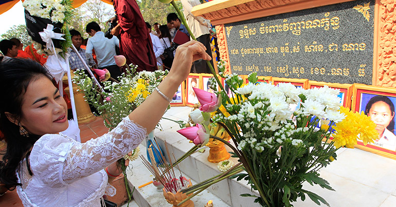 A Cambodian woman puts flowers to pray for victims who died in a grenade attack in 1997, at a stupa during a ceremony in Phnom Penh, Cambodia