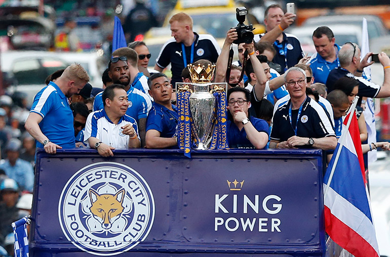 Riding in an open-air bus, Leicester City's Italian manager Claudio Ranieri (F-R), Thai Chairman Vichai Srivaddhanaprabha (2-L), his son Vice Chairman Aiyawatt Srivaddhanaprabha (F-2-R) and team players greet locals as they parade with their English Premier League trophy on a street in central Bangkok, Thailand