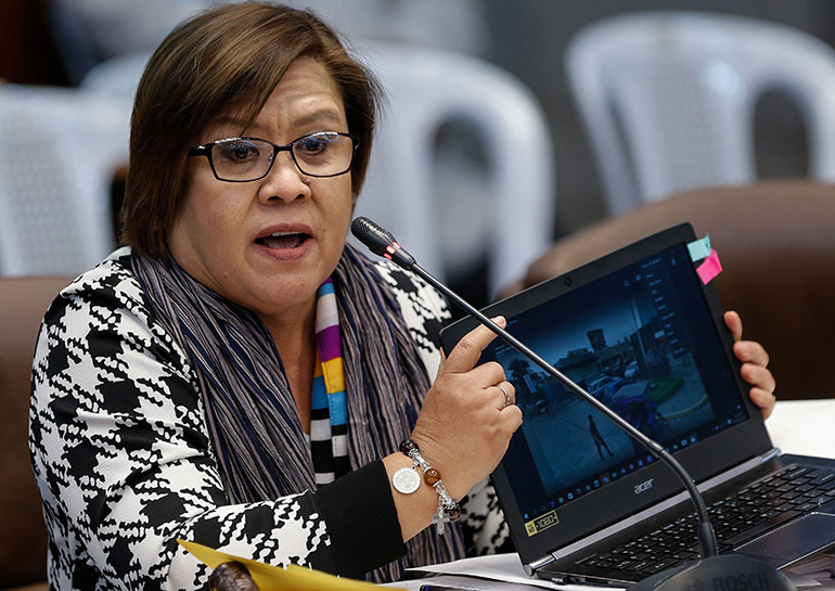 Senator Leila De Lima shows pictures of a crime scene on a laptop during a hearing on extrajudicial killings and summary executions of suspected criminals at the Philippine Senate in Pasay City, south of Manila, Philippines