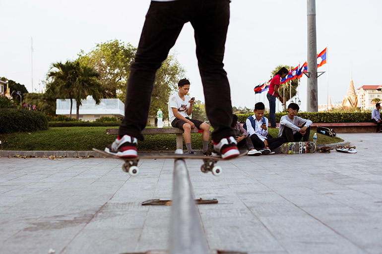 A group of skateboarders absorbed by their smartphones on Sisowath Quay in Phnom Penh