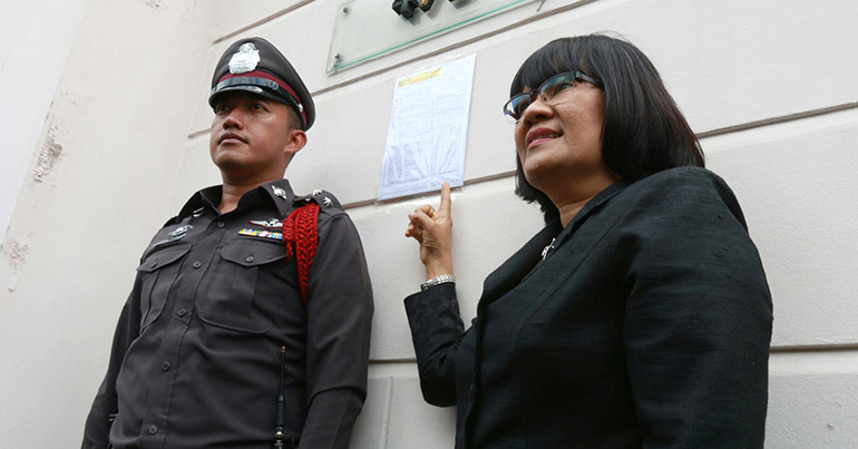 A Thai police officer and a revenue official put a tax form at the gate of coup-ousted and exiled former Thai Prime Minister Thaksin Shinawatra's ex-wife's house in Bangkok, Thailand