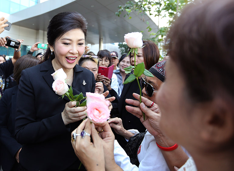 Former Thai Prime Minister Yingluck Shinawatra (L) receives flowers from supporters as she leaves after her hearing on criminal charges stemming from her government's rice price subsidy, at the Supreme Court's Criminal Division for Holders of Political Positions, in Bangkok, Thailand