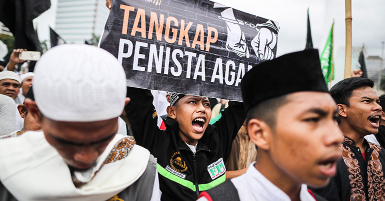 Protesters raise placards and shout slogans during a protest against Jakarta's governor near the presidential palace in Jakarta, Indonesia