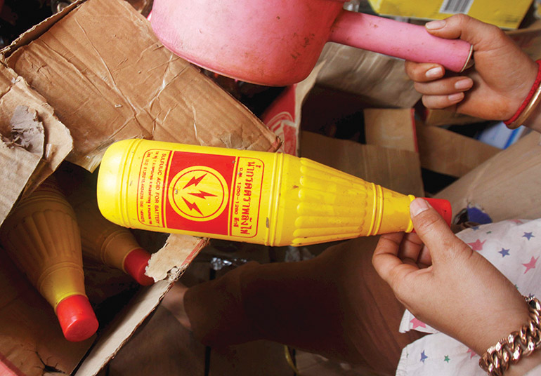 a Cambodian vendor unloads a bottle of sulfuric acid from a box at her shop near the Thai border in February 2010. Photo: Stefan V. Jensen