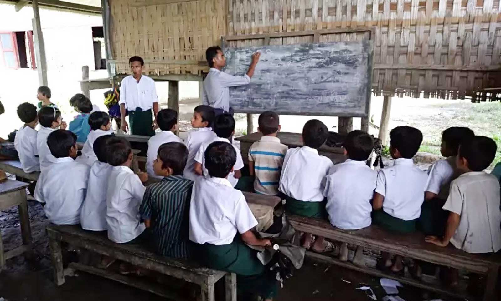 Young students gather together in a makeshift classroom to learn what they can from fellow villagers. Rohingya students in the Rakhine state have not had access to education for over two years. Photo: Muhammed Salam