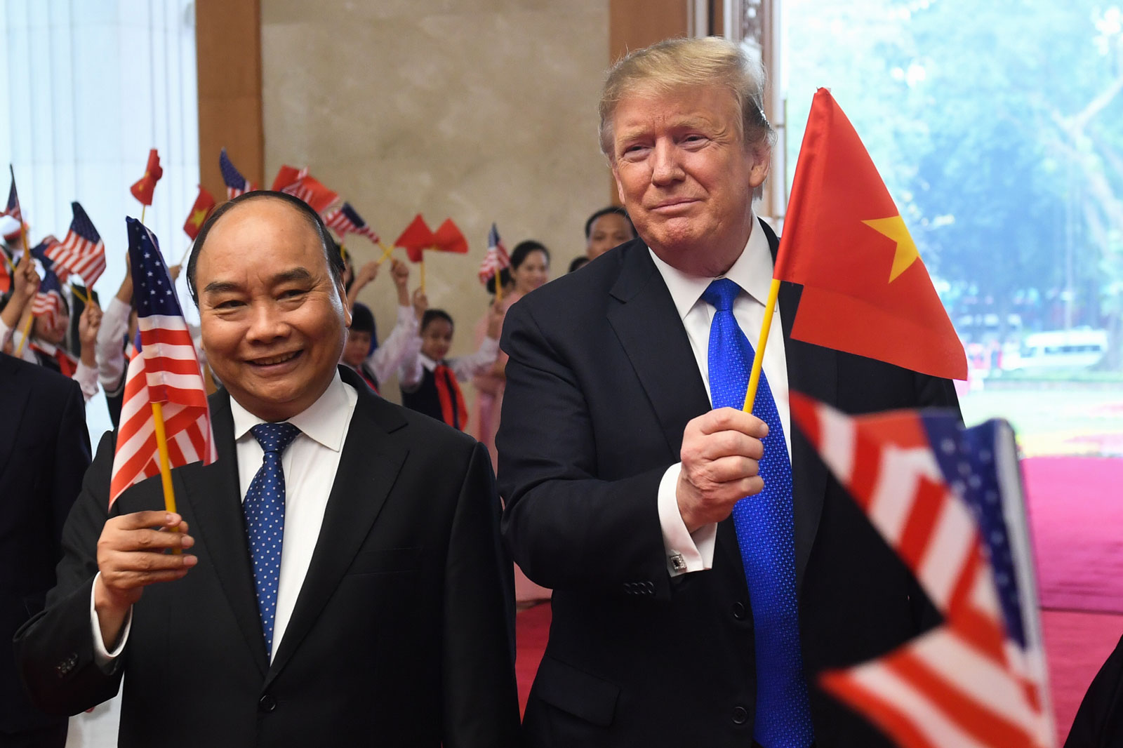 US President Donald Trump (R) holds a Vietnamese flag as Vietnam's Prime Minister Nguyen Xuan Phuc (L) waves a US flag upon their arrival for a meeting at the Government Office in Hanoi on February 27, 2019, ahead of the second US-North Korea summit. Saul LOEB / AFP