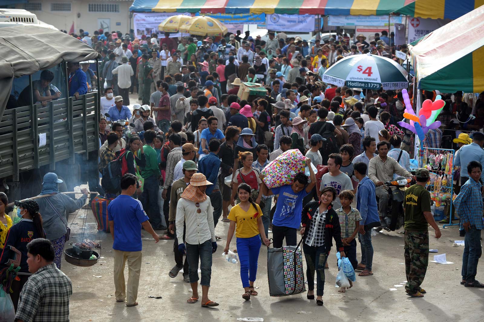 Cambodian migrant workers carry their belongings after arriving at Poipet city in Banteay Meanchey province on June 16, 2014 Photo: Tang Chhin Sothy / AFP)