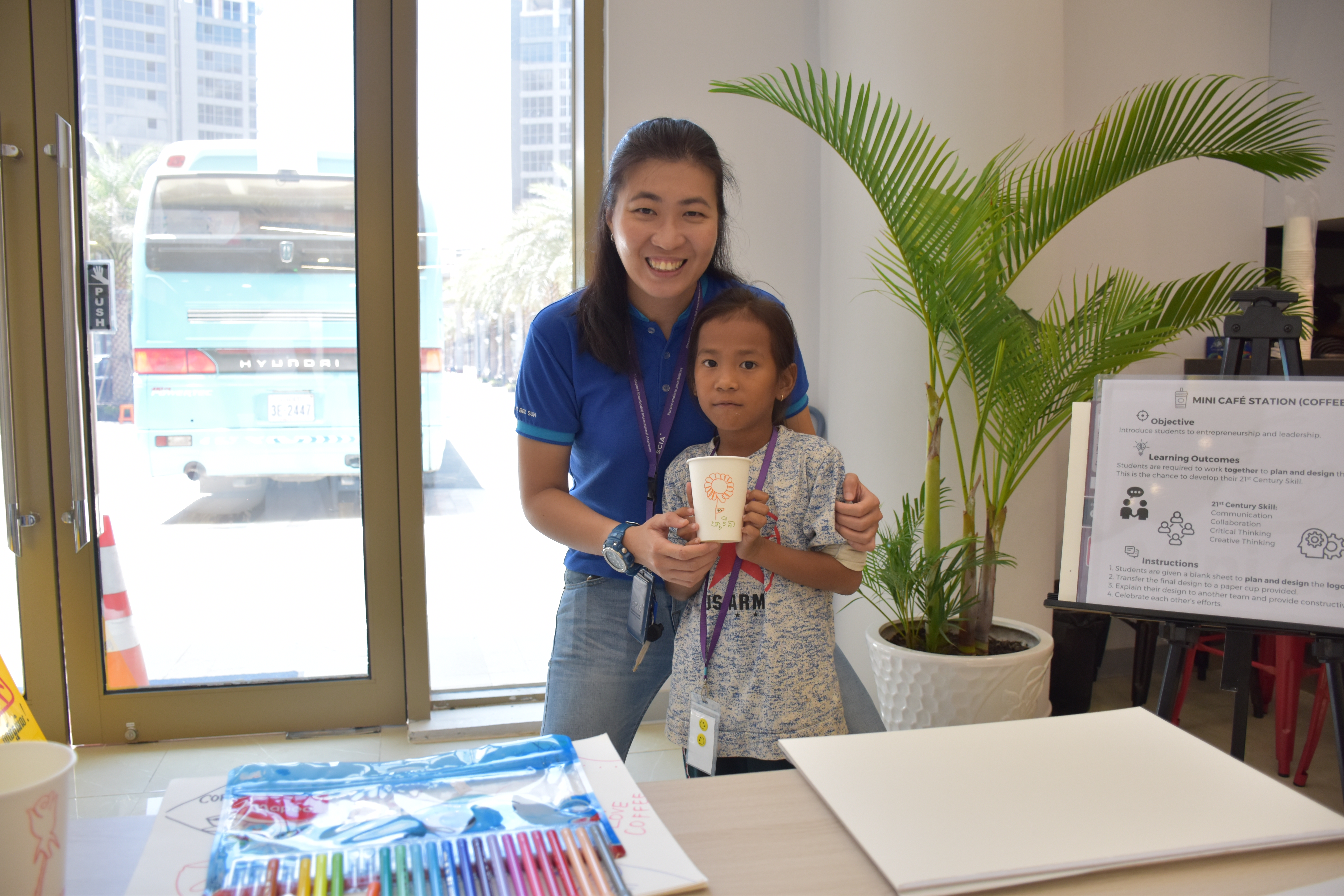 Ms Ng Bee Sun assisting a local student in designing a logo for the mini café at the café career station