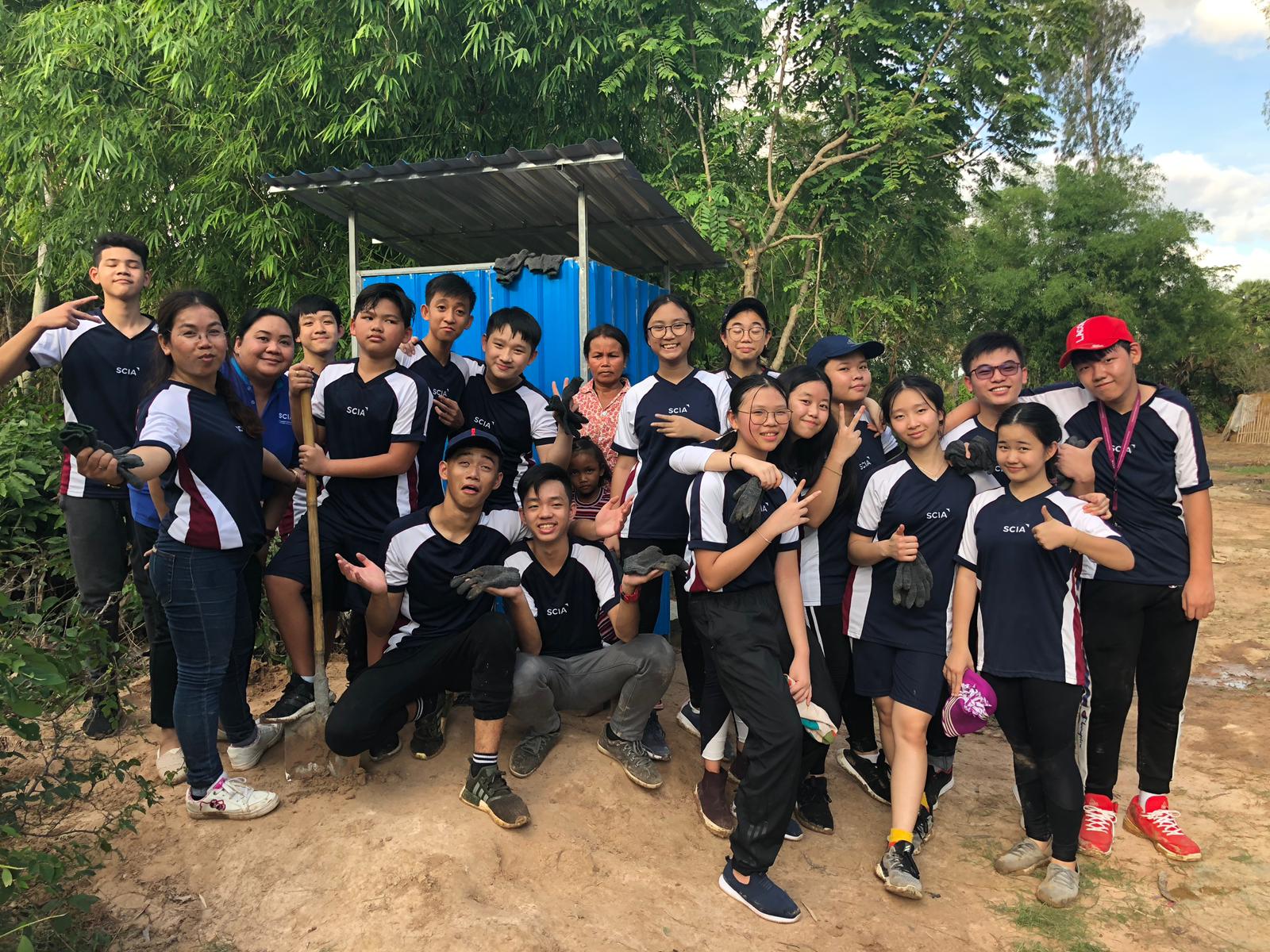 Grade 8 and Grade 9 SCIA students posing in front of their proud accomplishment: a toilet for the local village