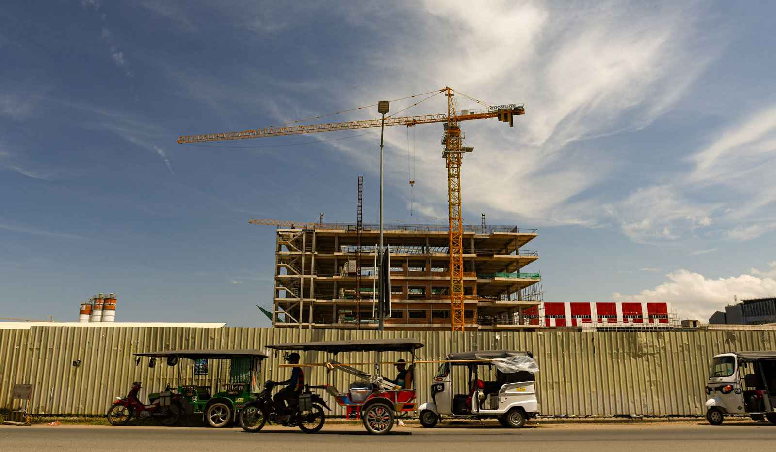 Tuktuks await passengers in the the shadow of a building site opposite an Aeon shopping mall in Phnom Penh. Photo: Simon Roughneen