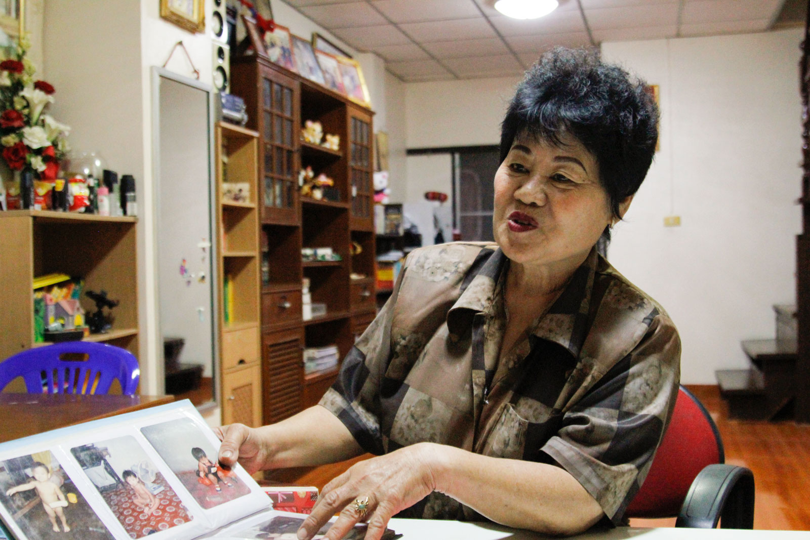 Kanya Theerawut going through a photo album containing images of her missing son. Photo: Caleb Quinley