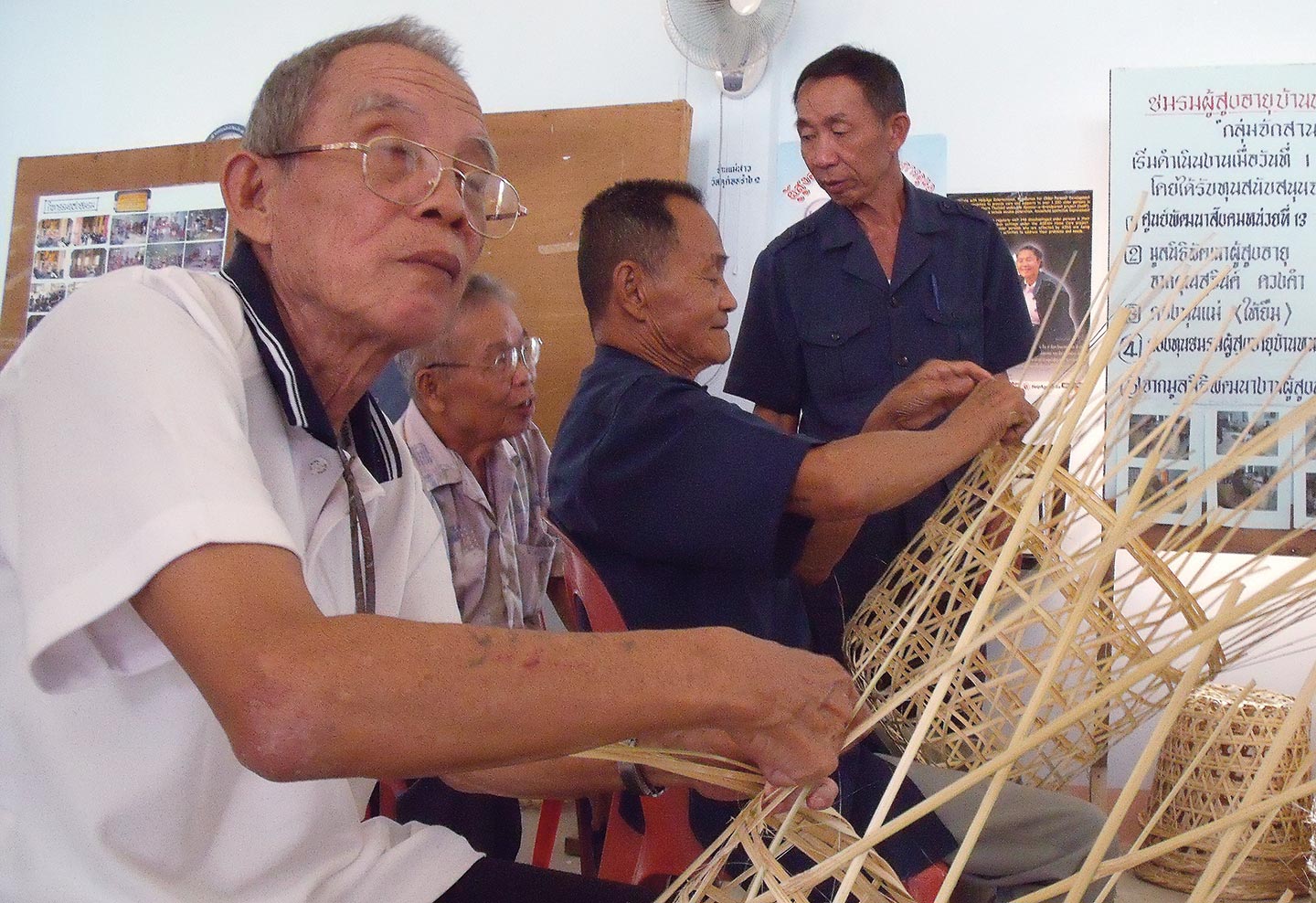 Weaving spell: despite a paralysed right hand, Rong Phroa (left) makes 500 baht a month by making baskets at the home, which helps pay for his monthly visits to the doctor. Photo: Tiep Seiha