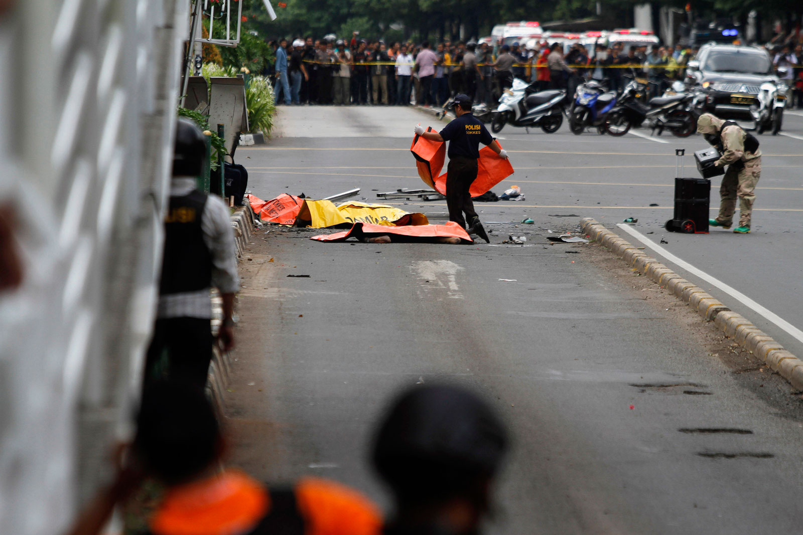 An Indonesian police officer places body bags over victims' at the scene of a terrorist attack in Jakarta on 14 January 2016, in which 7 people were killed. Photo: EPA/Roni Bintang