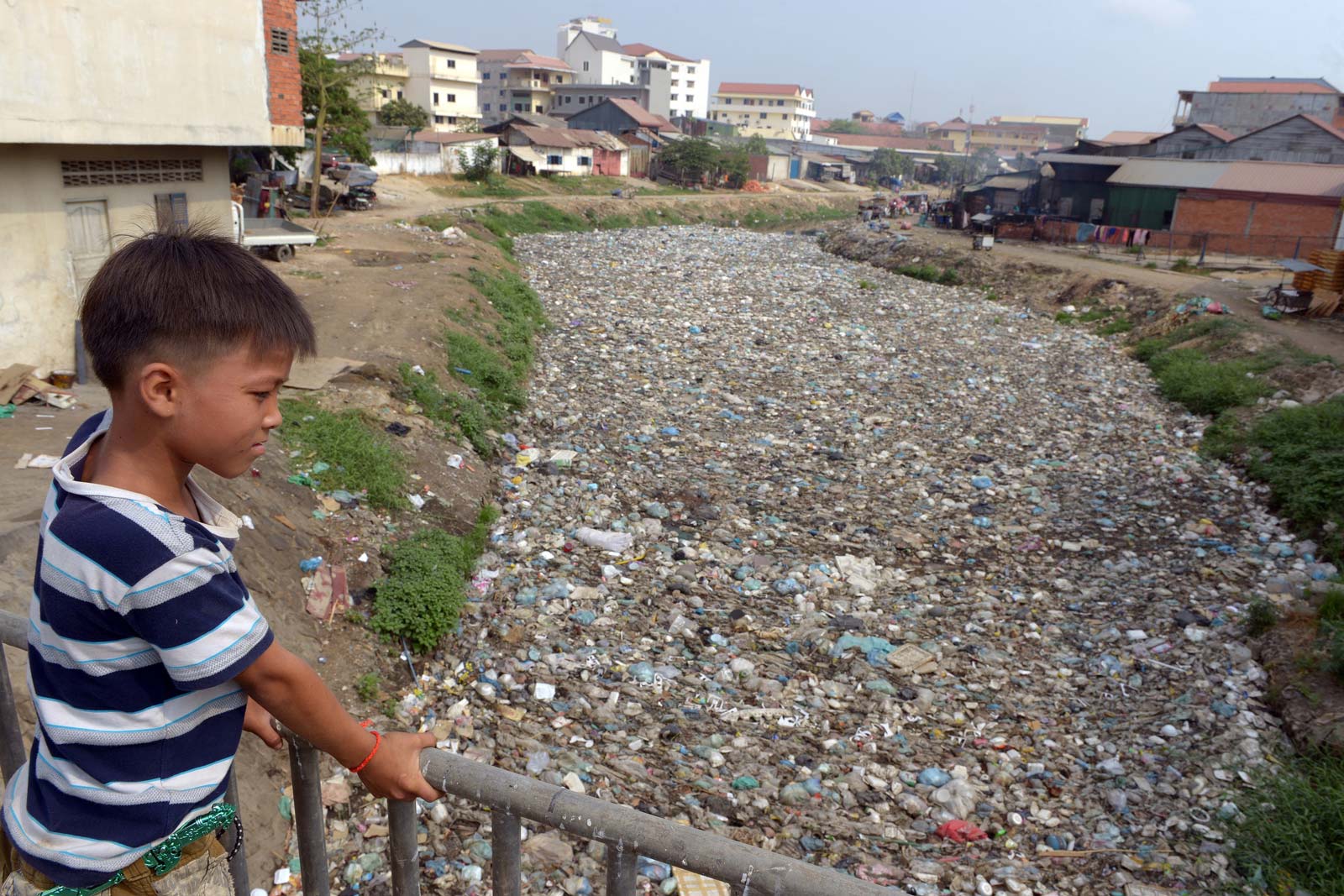 A Cambodian boy looks out over a canal filled with waste in Phnom Penh on March 4, 2015. Photo: Tang Chhin Sothy/AFP